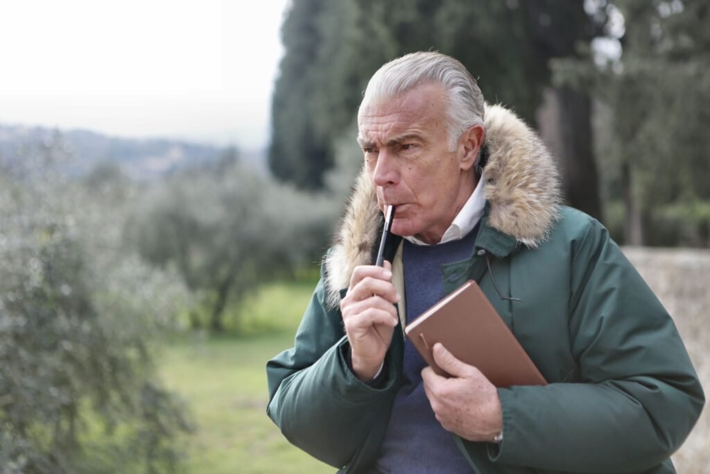 Un sénior avec un stylo et un carnet en pleine réflexion
